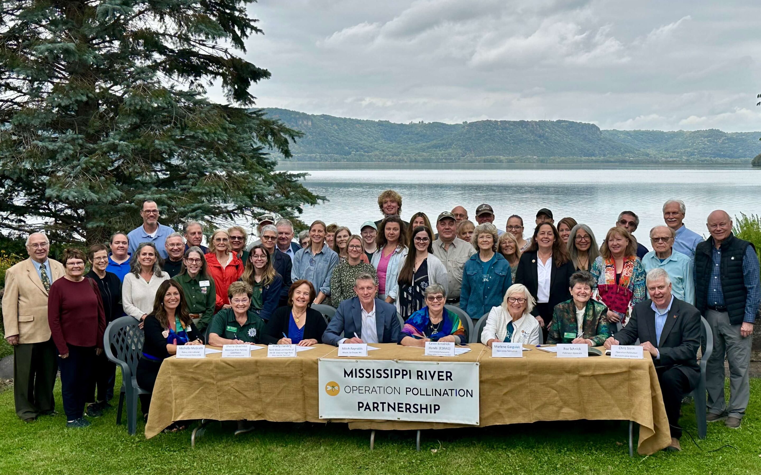 Group of people, representing the Mississippi River Operation Pollination Partnership, in front of river.